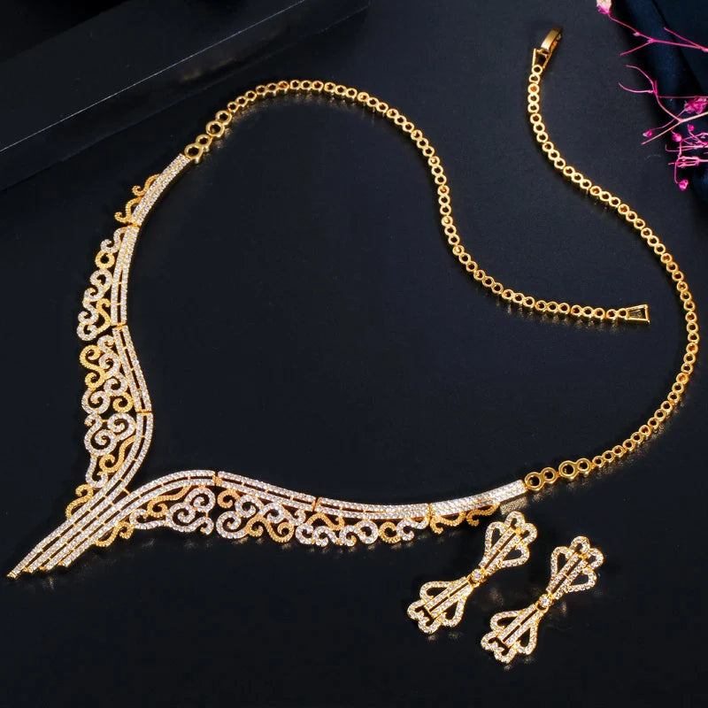 Gold-tone necklace with sparkling scrollwork and matching drop earrings arranged below