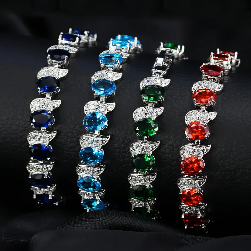 Oval crystal tennis bracelet with leaf-shaped accents in blue, green, and red options