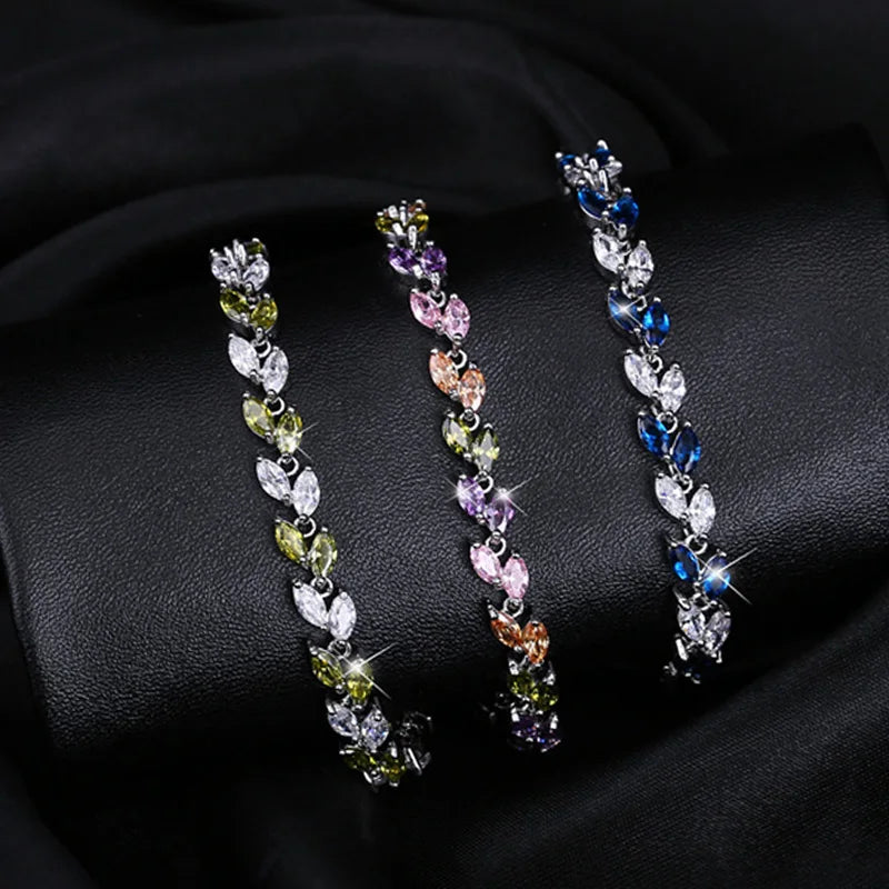 Three silver-tone leaf-link bracelets with green, multicolor, and blue stones