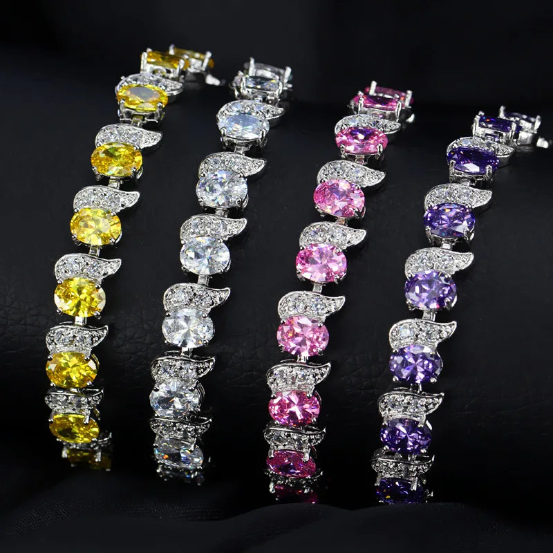 Oval crystal tennis bracelet with leaf-shaped accents in yellow, clear, pink, and purple options