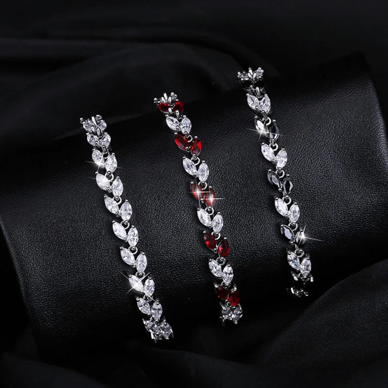 Three silver-tone leaf-link bracelets with clear, red, and dark stones