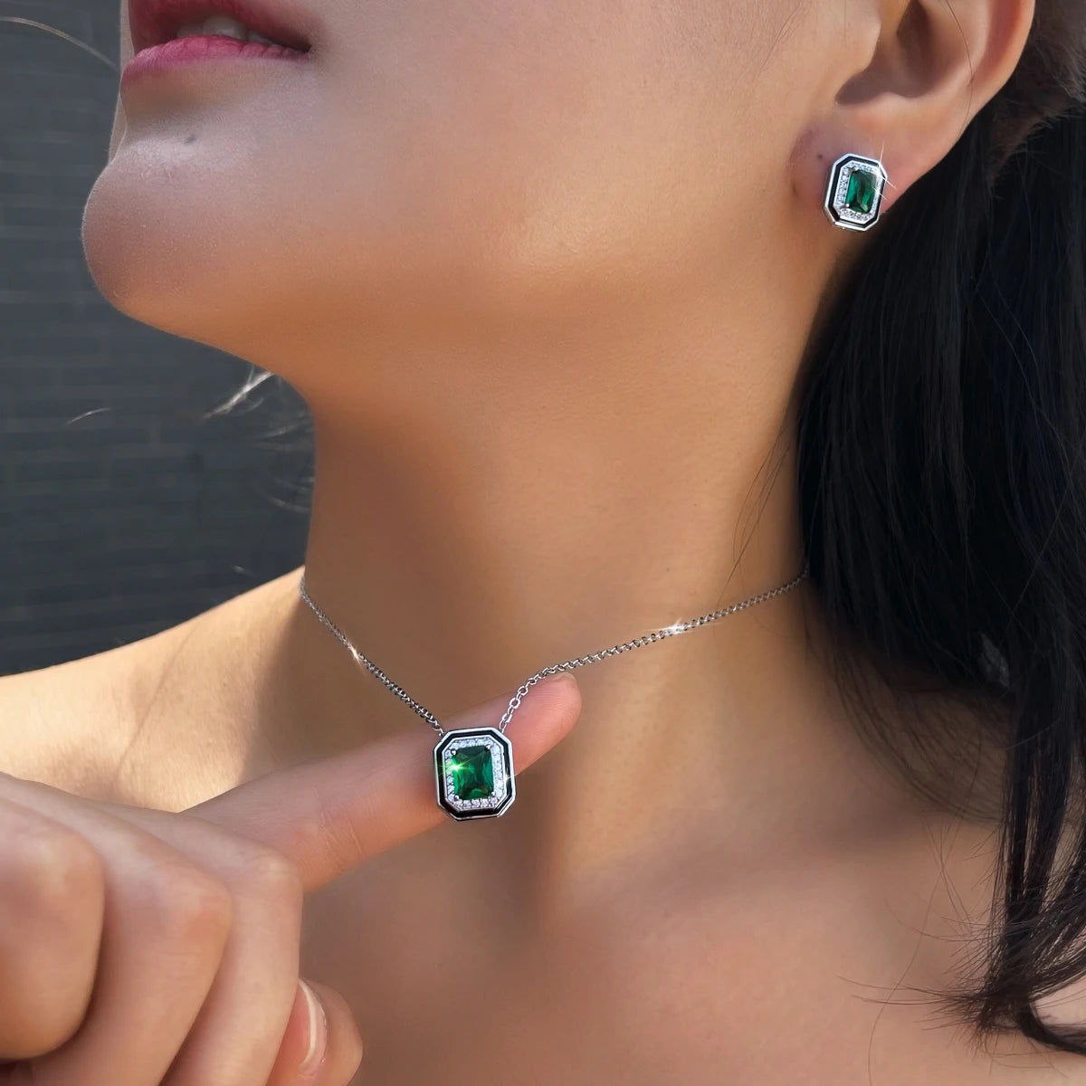 Green crystal pendant necklace and matching stud earring, shown worn at the neck