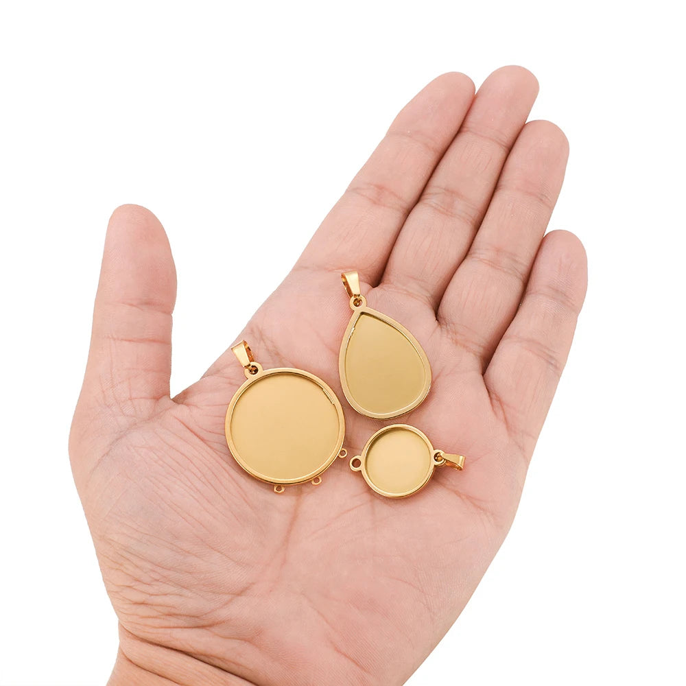 Round gold-tone cabochon pendant settings with bails held in palm