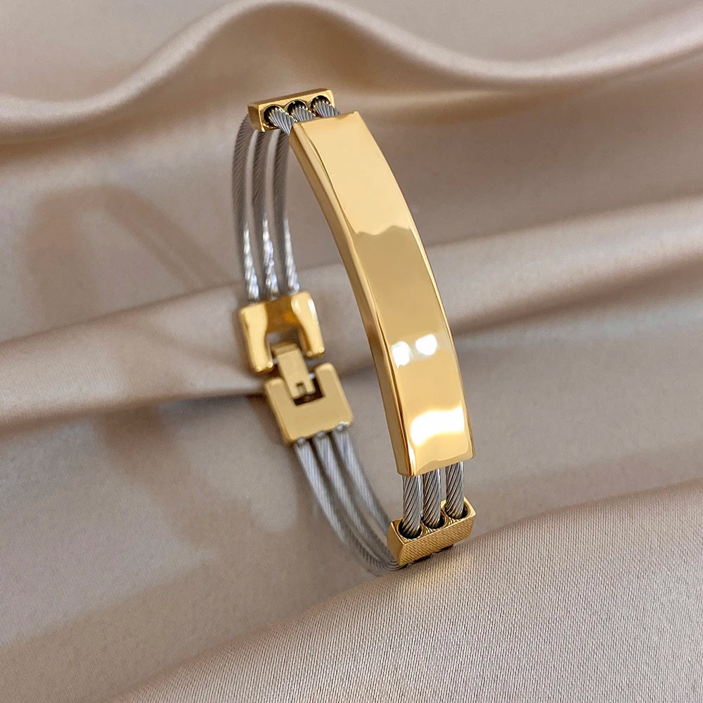 Gold and silver chunky cuff bangles with clasp link accents and elastic-style cords