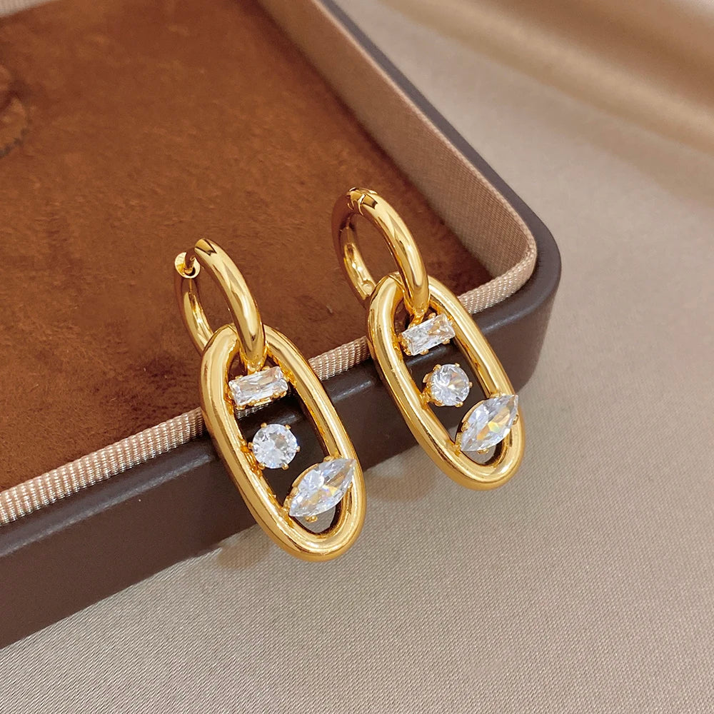 Gold-plated hoop earrings with zircon stones on a jewelry box