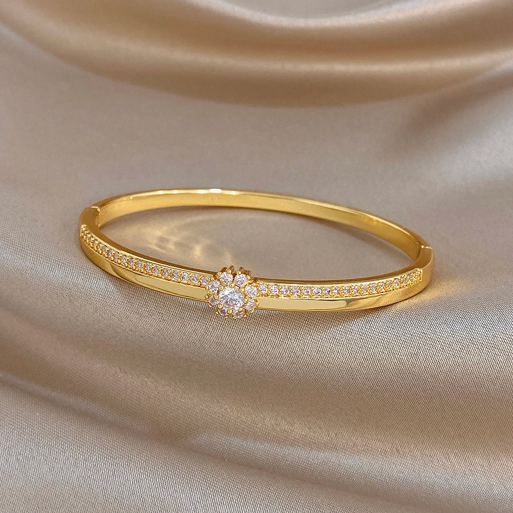 Gold-plated bangle with continuous zircon pave and central flower cluster