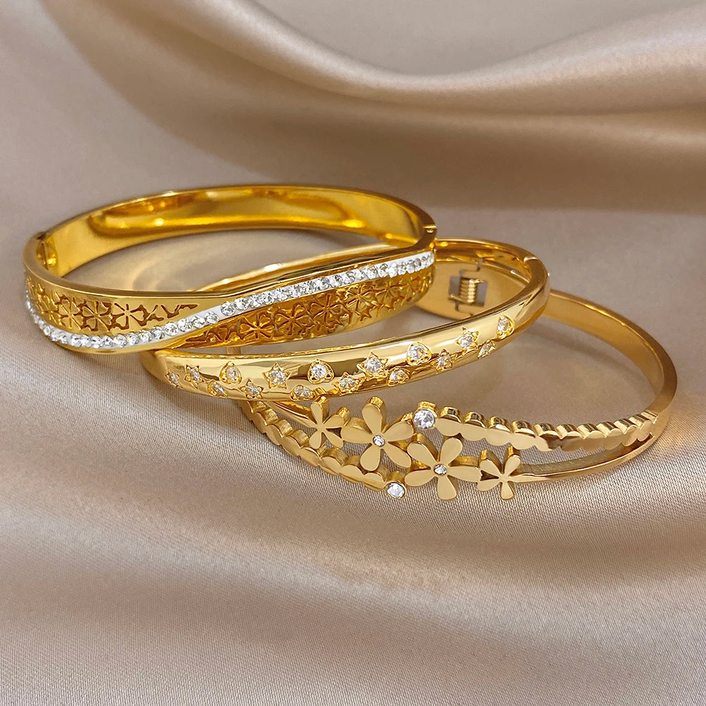 Gold cuff bangle set with crystal stripe, engraved band, and daisy floral charm