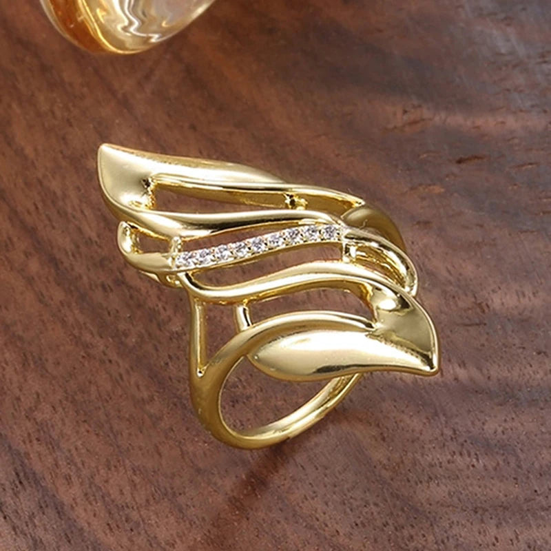 Gold-tone openwork geometric ring with central crystal inlay and curved shield shapes