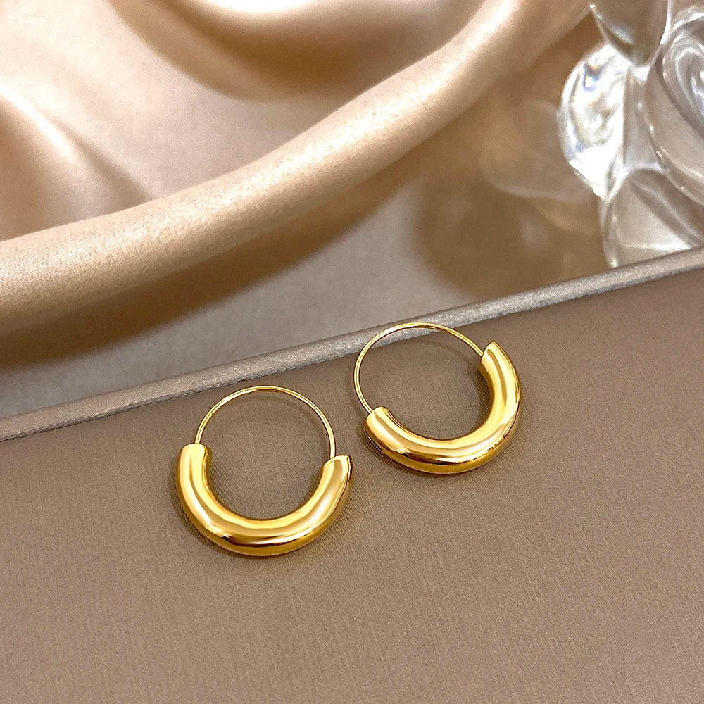 Gold-tone geometric hoop earrings with glossy, rounded lower halves