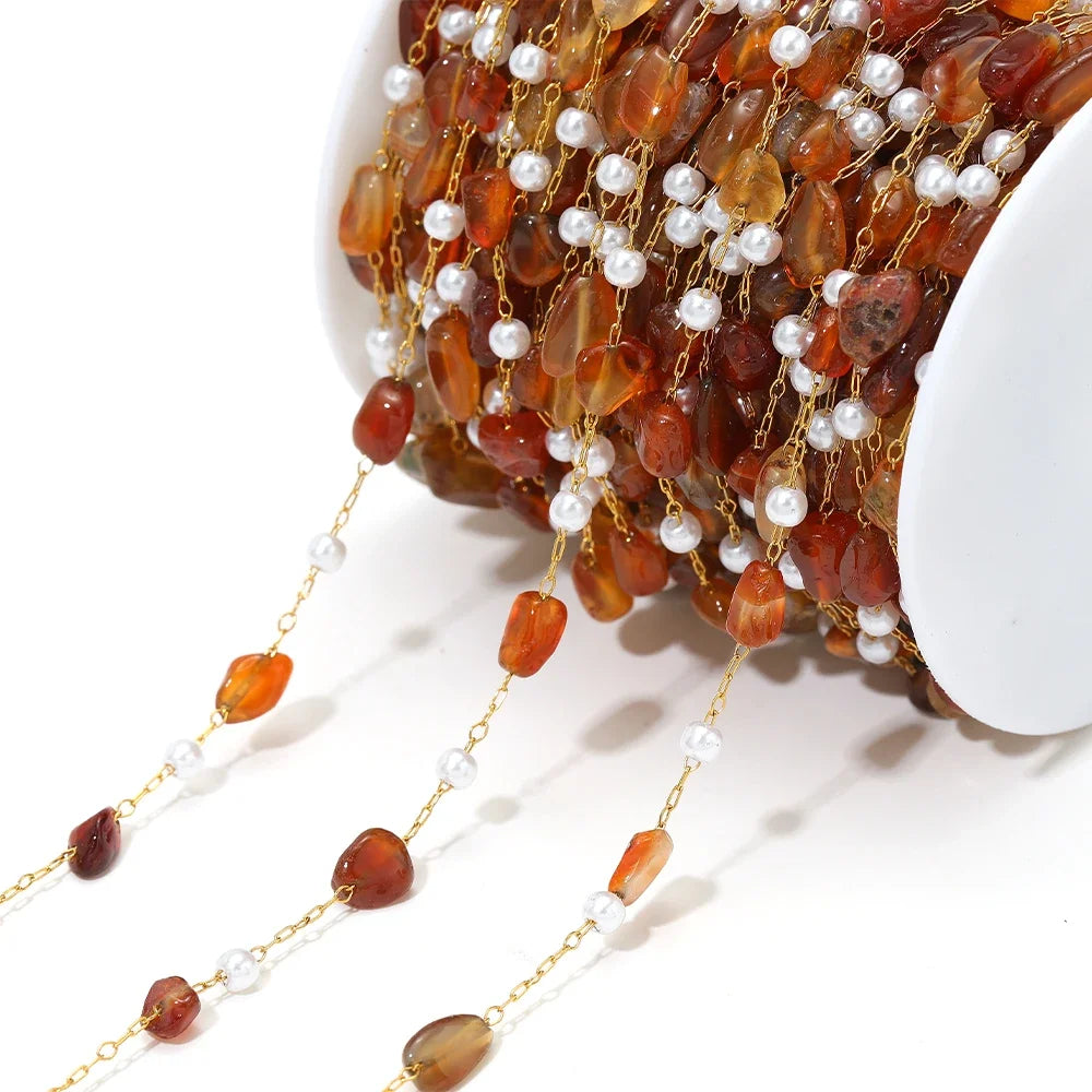 Irregular stone bead chain with pearl accents on gold-toned links, amber orange beads