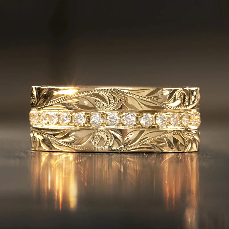 Gold carved wedding band with clear channel-set stones and ornate leaf engraving