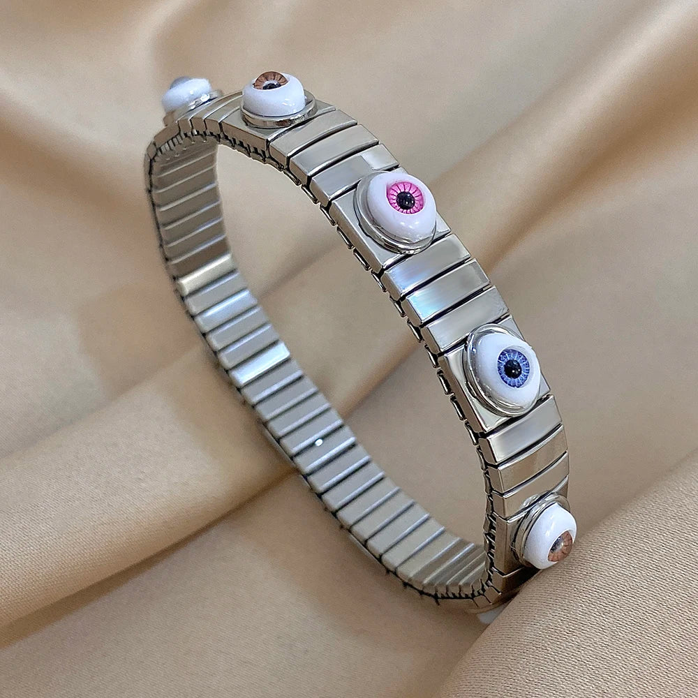 Silver-tone elastic bracelet with ridged metal links and multicolor evil eye bead details