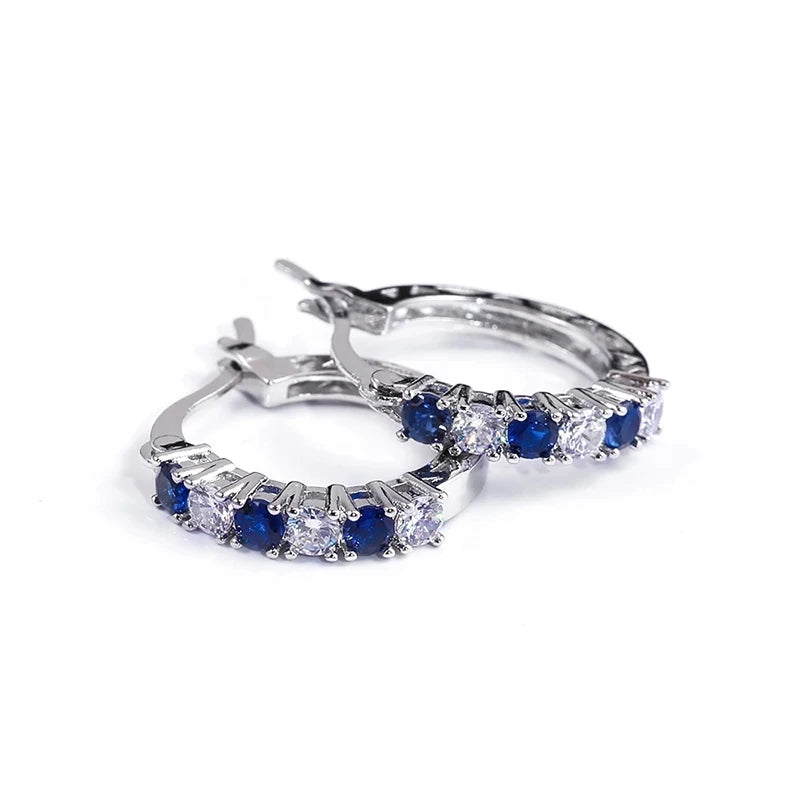 Silver circle hoop earrings with blue and clear stones along the band