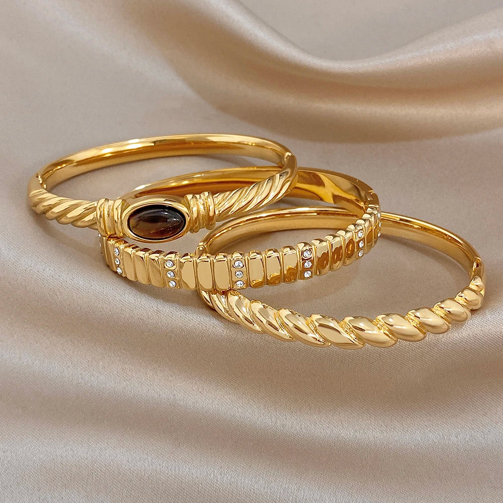 Gold-tone oval stone cuff bangle with textured twist and rhinestone band