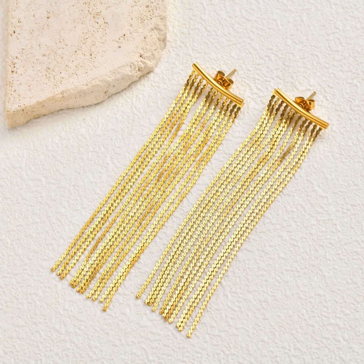 Gold chain fringe tassel earrings with clip backs, close-up view