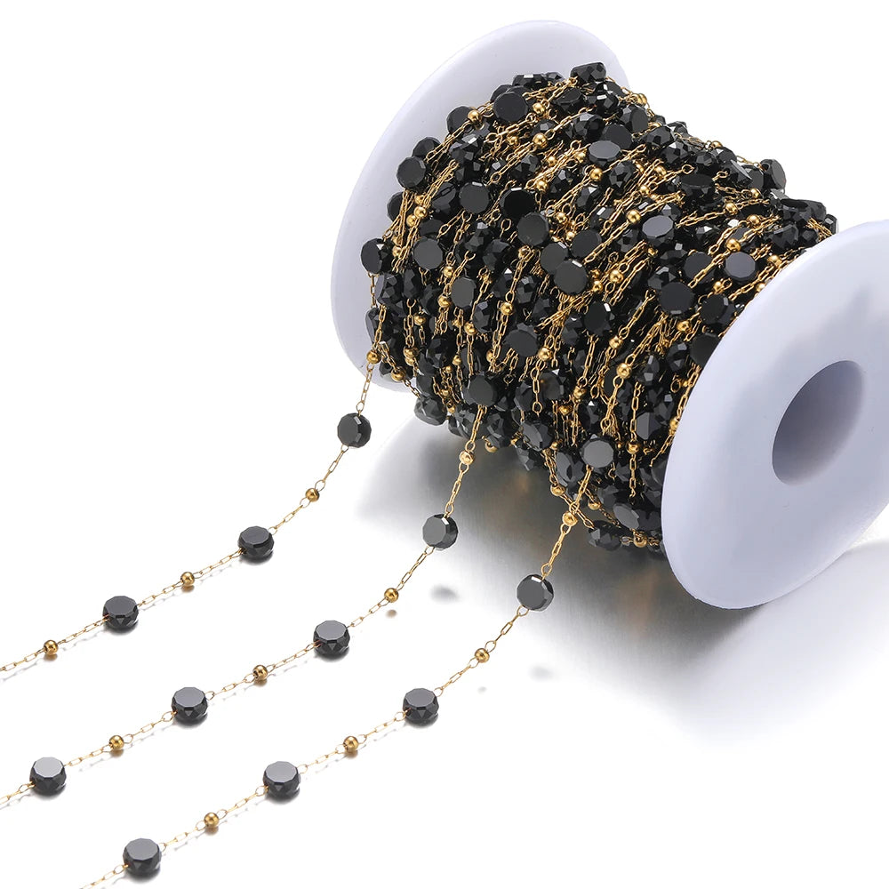 Black crystal bead chain with gold links on a white spool for DIY jewelry making