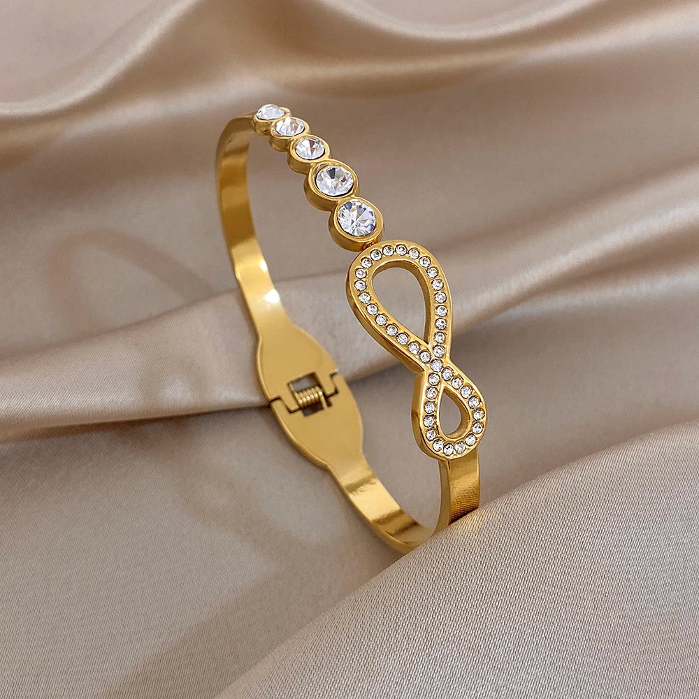 Gold-tone rhinestone infinity cuff bracelet with round crystal accents and hinge clasp