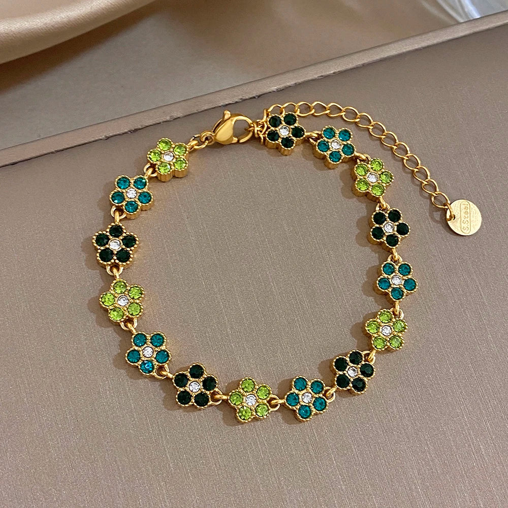 Gold-tone bracelet with green, teal, and black flower zircon beads and round extender tag