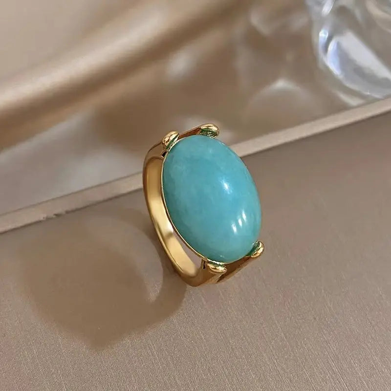 Gold-tone ring with large turquoise oval stone and bezel prong setting