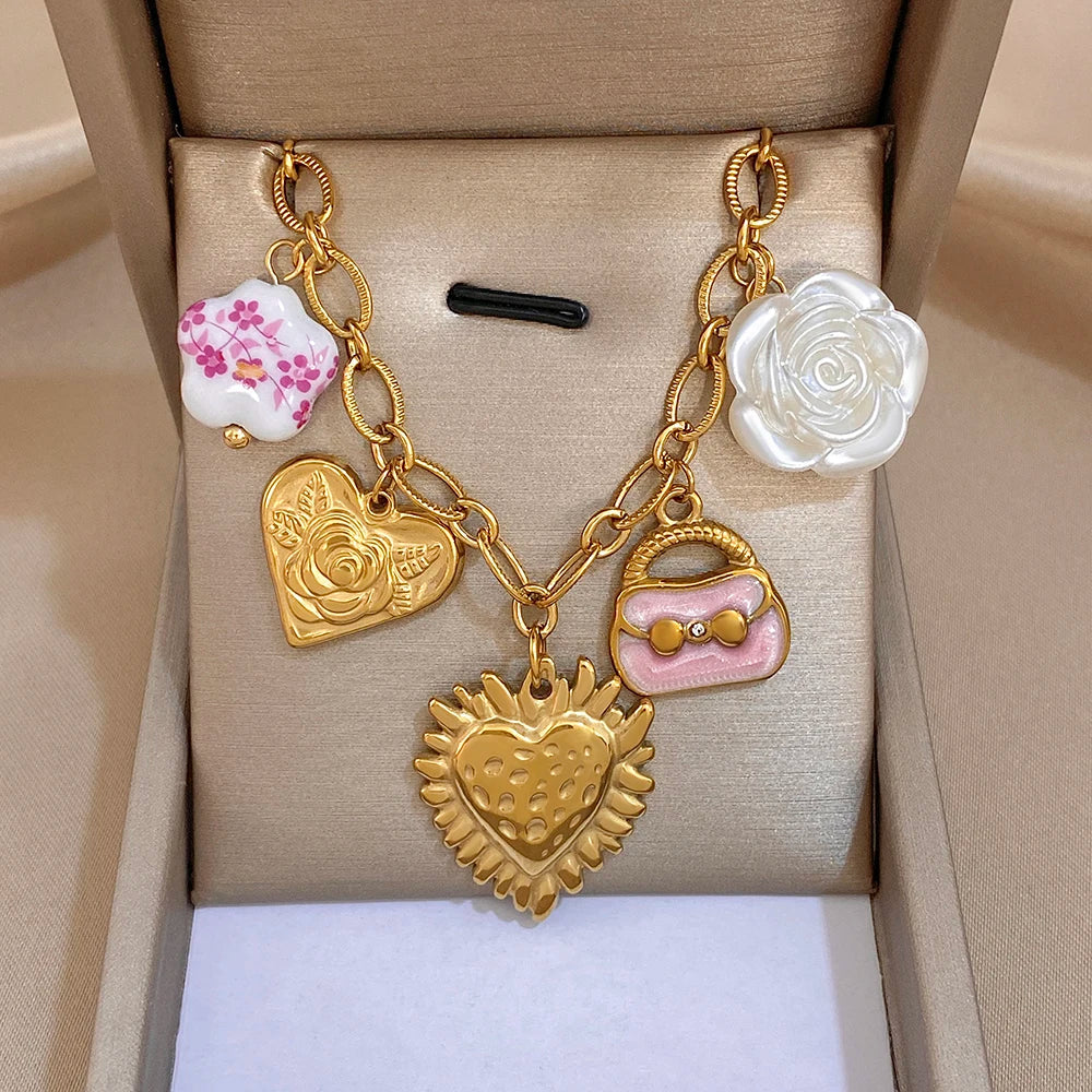Gold chain necklace with white rose charm, pink heart charm, and strawberry-style pendant