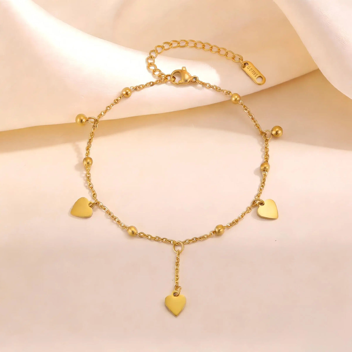 Gold heart beaded anklet with small heart charms and a hanging heart pendant, close-up