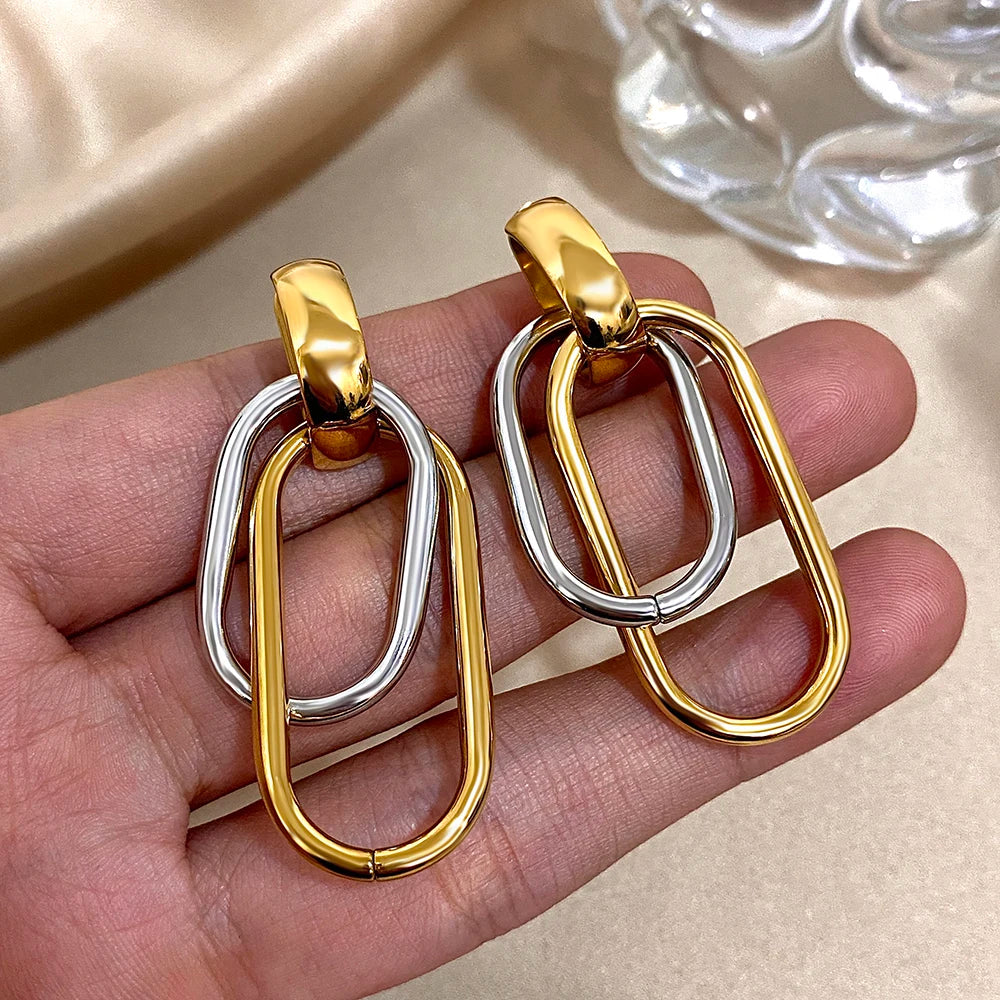 Gold and silver double-link earrings shown in hand for scale
