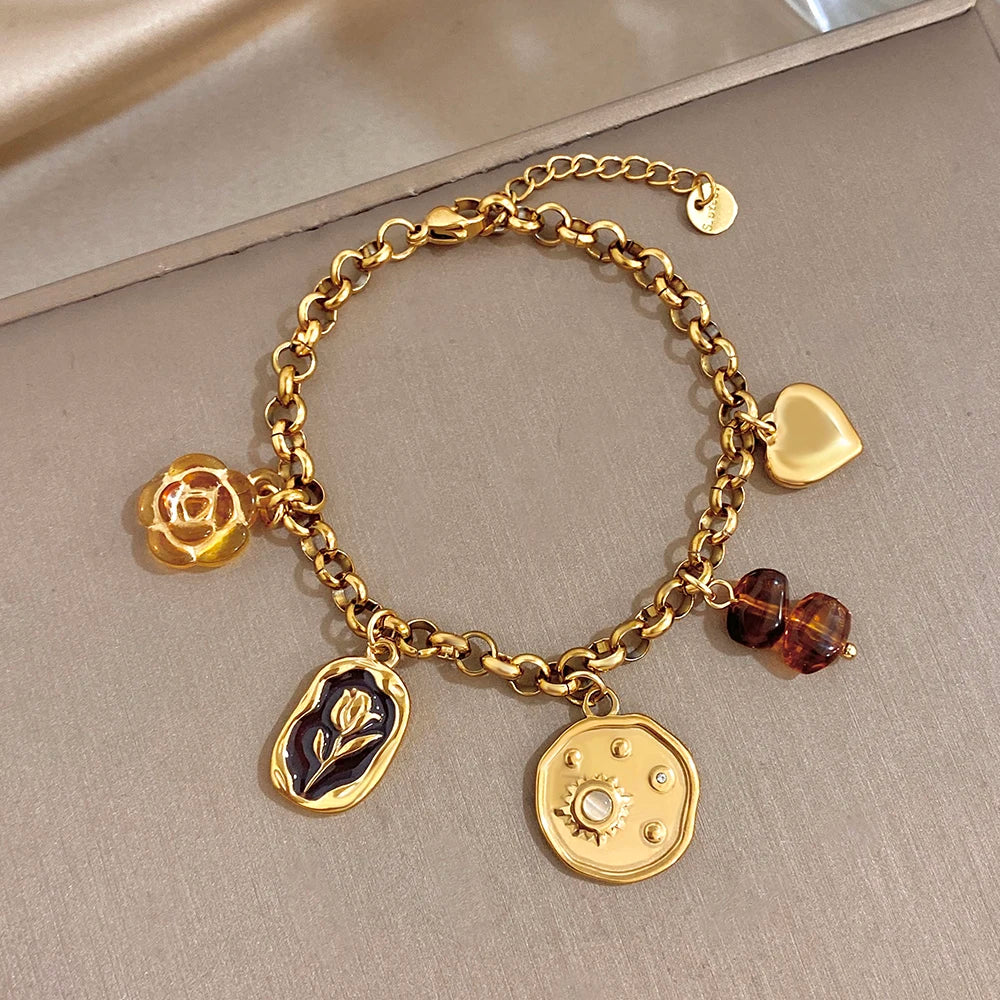 Gold plated charm bracelet with heart charm, rose, leaf, round gear coin, and amber beads