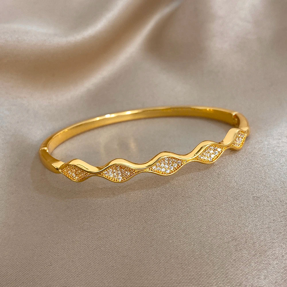 Gold-plated wave cuff bangle with glittering stone accents, curved profile