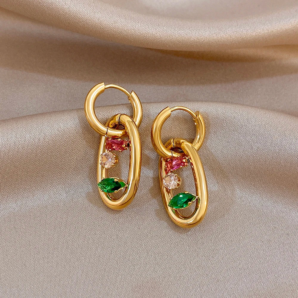 Gold oval hoop earrings with pink and green stones plus clear gem highlights