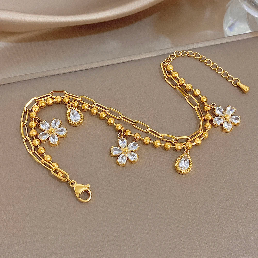 Gold-plated chain bracelet with multiple crystal flower charms and teardrop accents