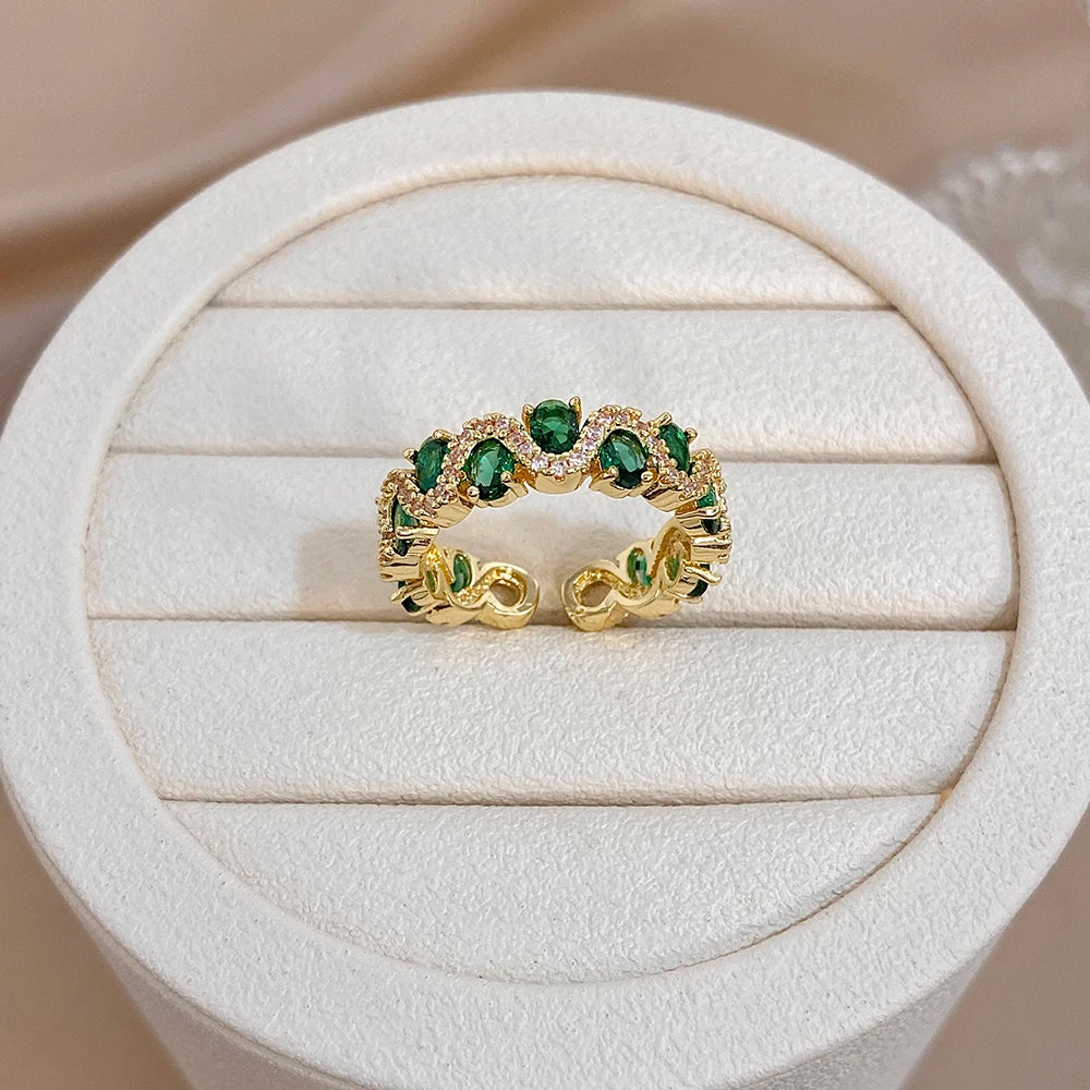 Gold-tone ring with green heart stones and sparkling halo detailing
