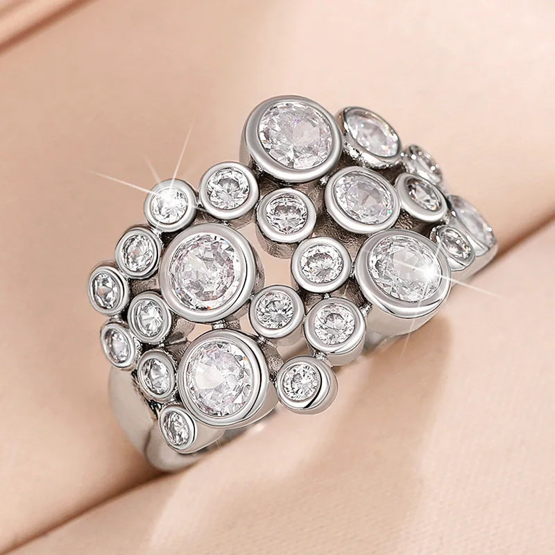 Silver-toned cluster ring with multiple round cubic zirconia stones on a curved band