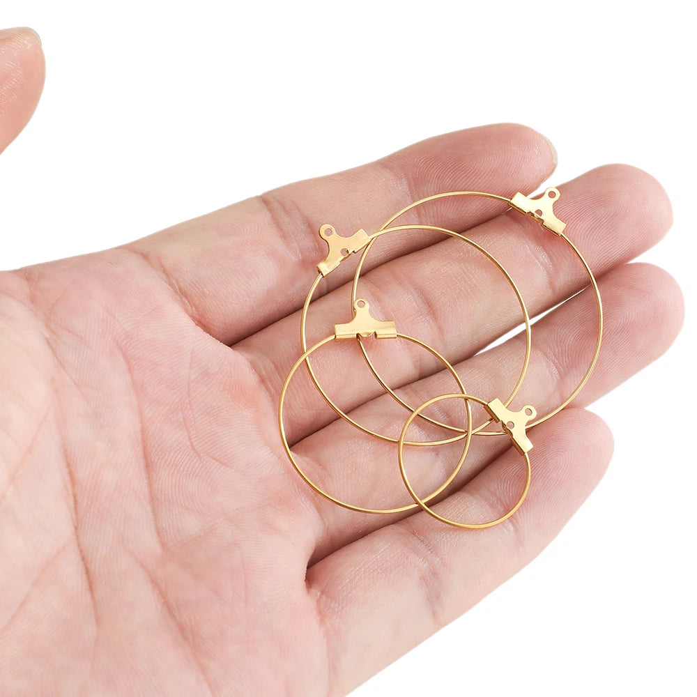 Gold hoop earring findings held in hand, circular hoops with clasp hook closures