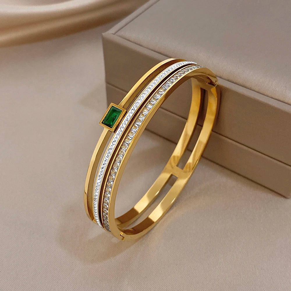 Gold-tone cuff bracelet angled view with green square centerpiece and white crystal trim