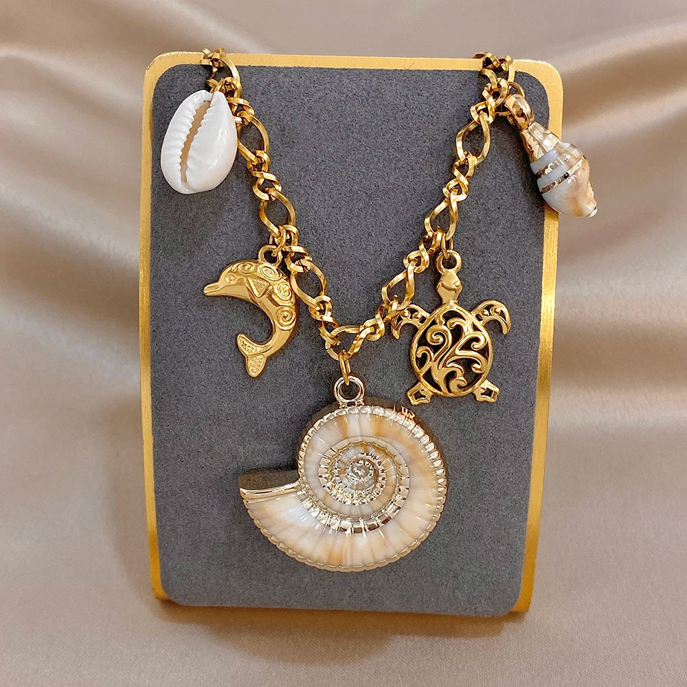Gold-tone charm necklace and bracelet set with large seashell spiral pendant and dolphin charm