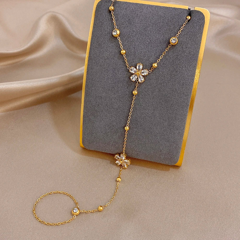 Gold-plated flower charm bracelet on display with linked finger ring chain
