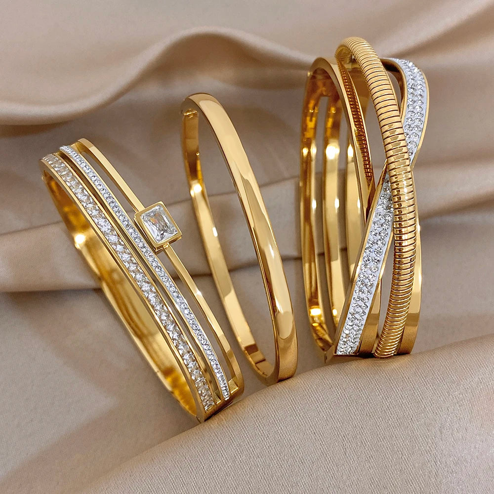 Set of gold-plated cuff bangles with clear zircon accents and textured bands