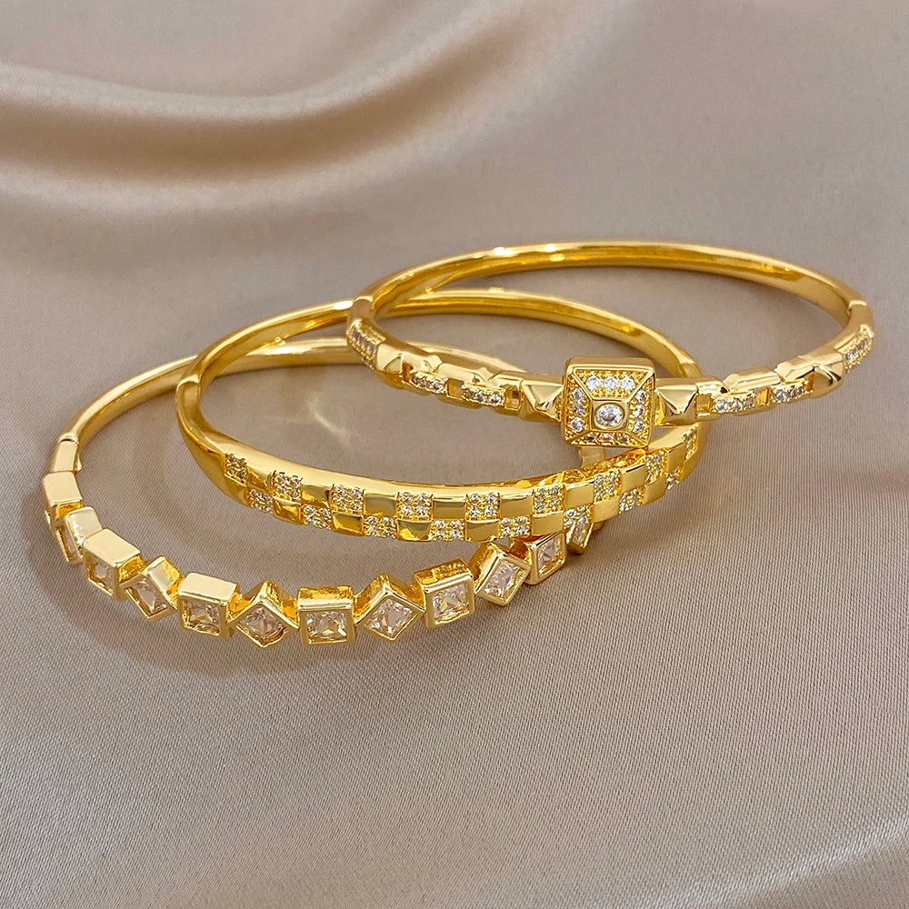 Gold-plated cuff bangles featuring square zirconia link bands and a central square