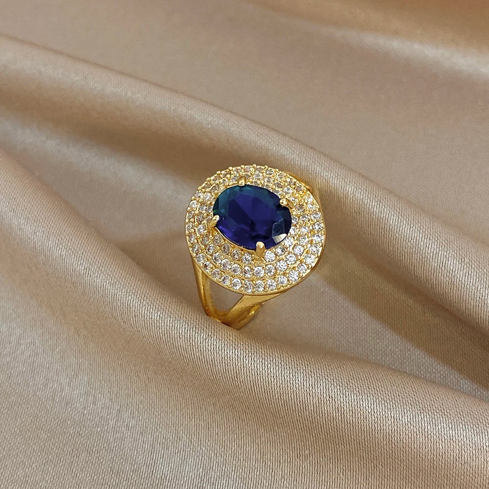 Gold-tone zircon open ring with oval blue center stone and bright crystal halo