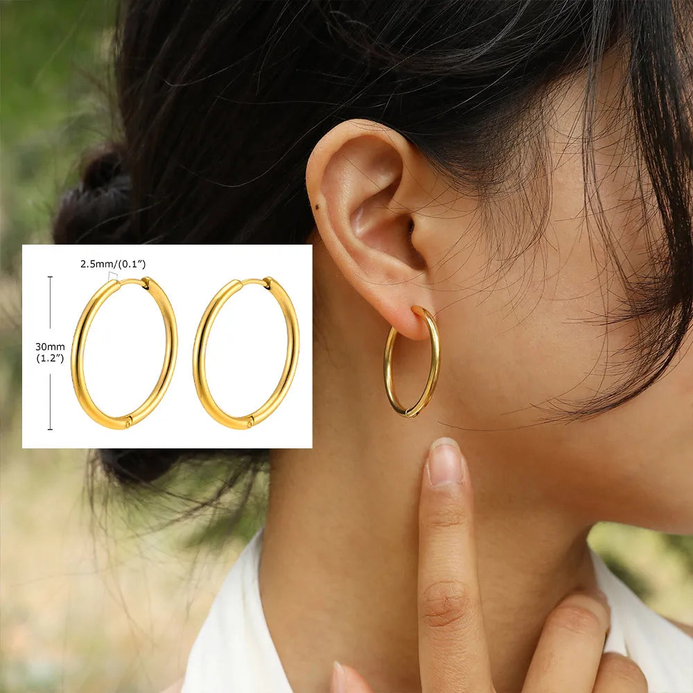 Gold-tone oval hoop earrings, shown worn and with a 30 mm size guide.