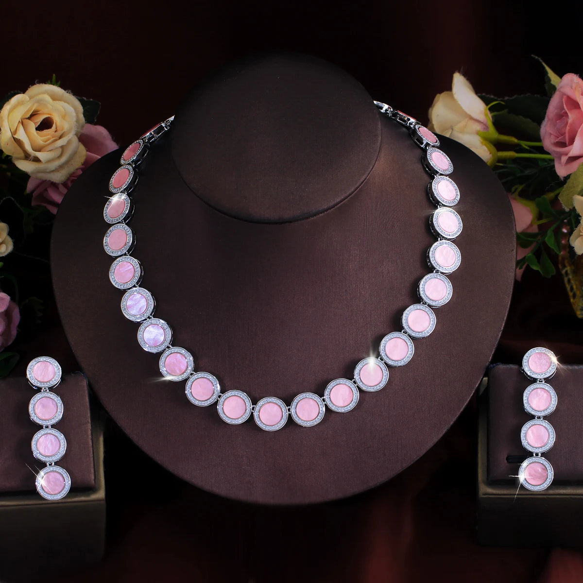 Pink round halo necklace and matching drop earrings displayed on stands