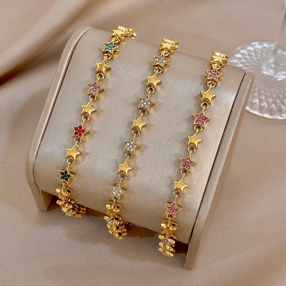 Three gold-tone star charm bracelets with multicolor gem inlays and chain clasps