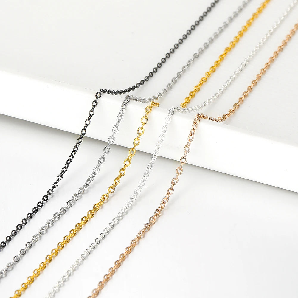 Assorted thin metal chain strands in black, silver, gold, and rose gold on a display