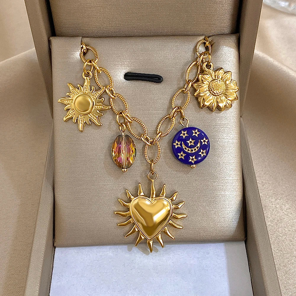 Gold chain necklace with star sunburst charm, blue moon disk, and heart pendant