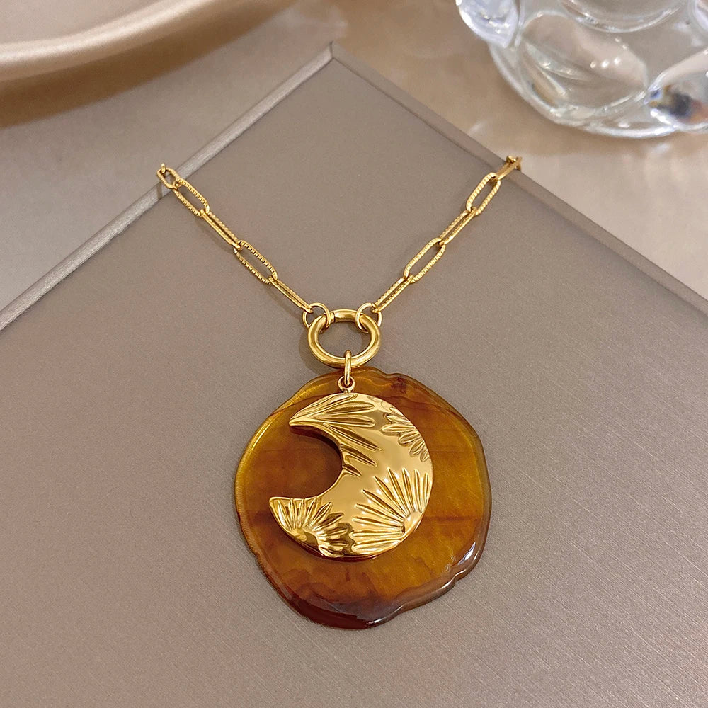 Gold-tone chain pendant necklace with amber round moon charm and crescent cutout detail