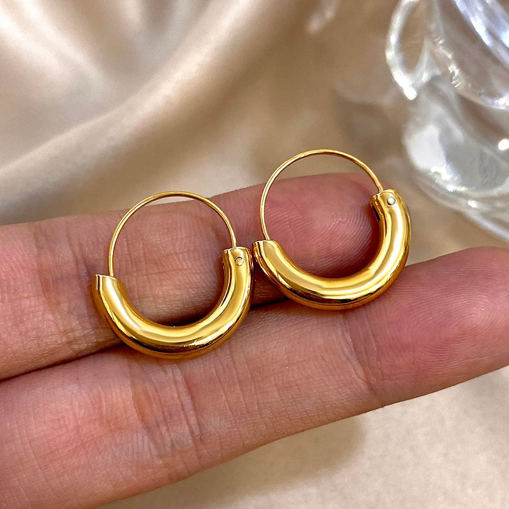Gold-tone hoop earrings shown close up, with chunky curved lower sections