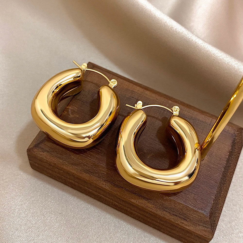 Gold-tone chunky hoop earrings with visible hinged posts and rounded U-shaped fronts