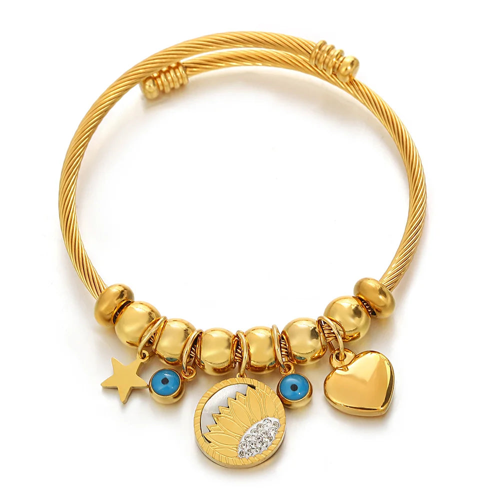 Gold-tone charm bracelet with star, blue eye beads, heart dangle, and round medallion