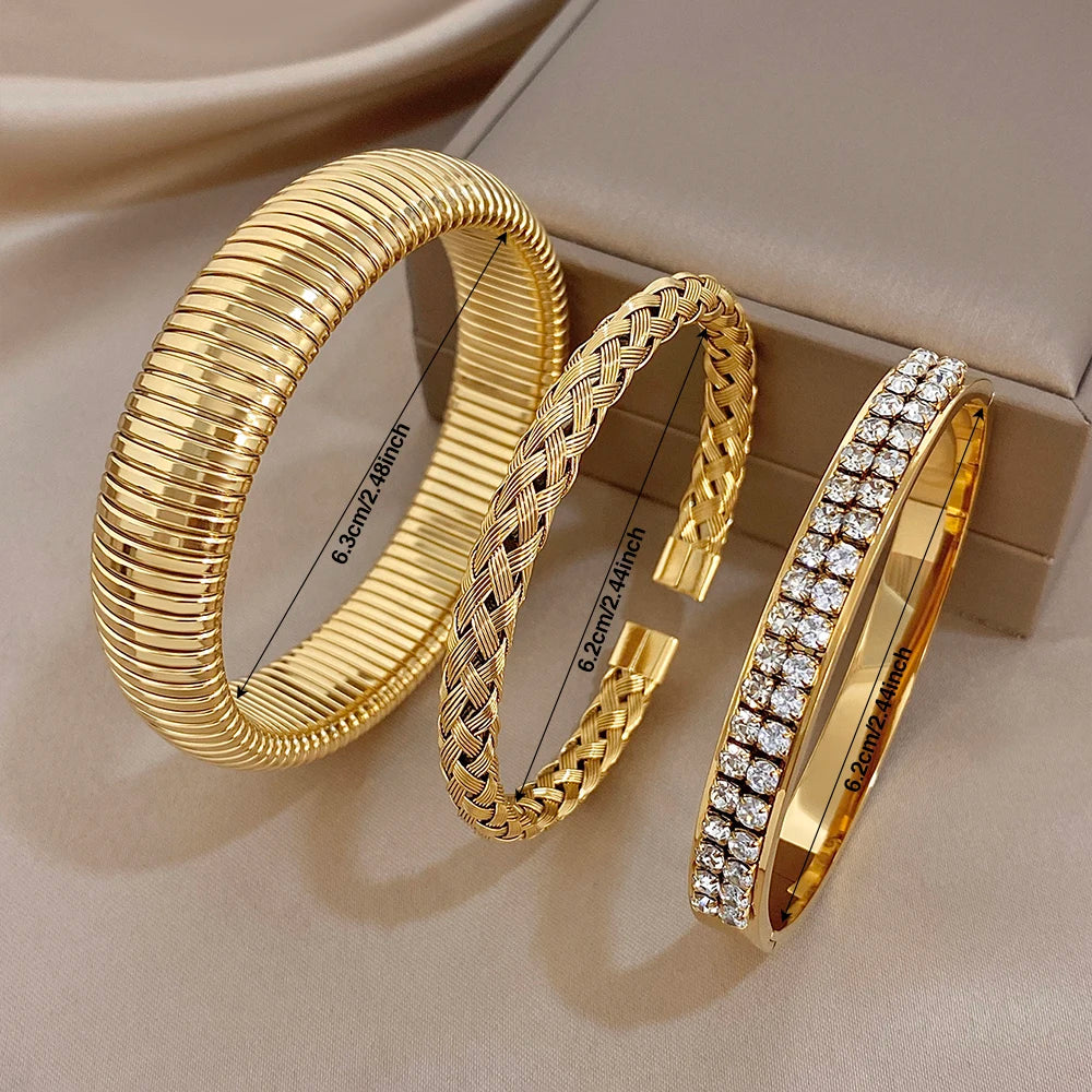 Gold-tone ribbed cuff bangles, braided bracelet, and zircon pave bangle on box