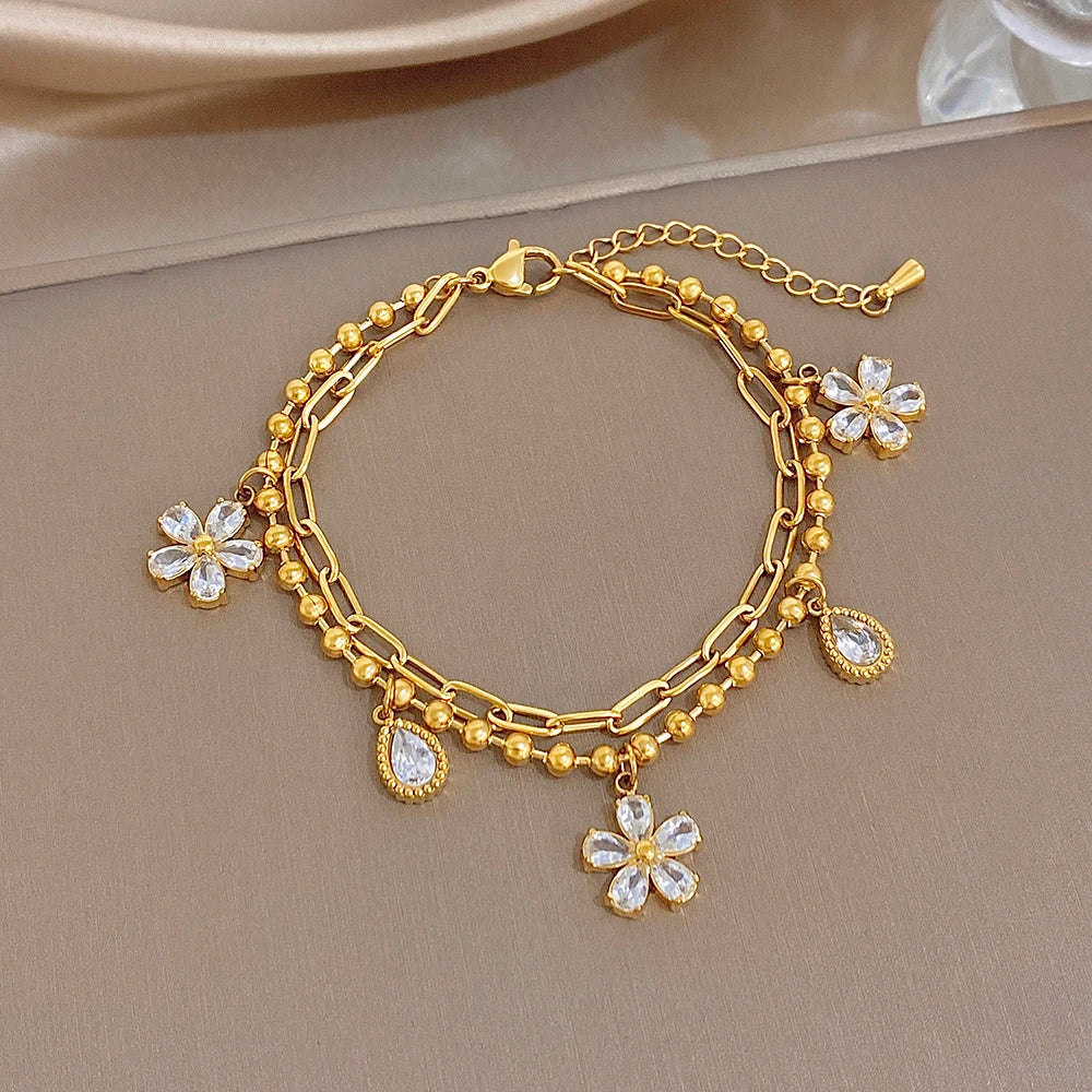 Gold-plated chain bracelet with crystal flower pendants and teardrop charm dangles